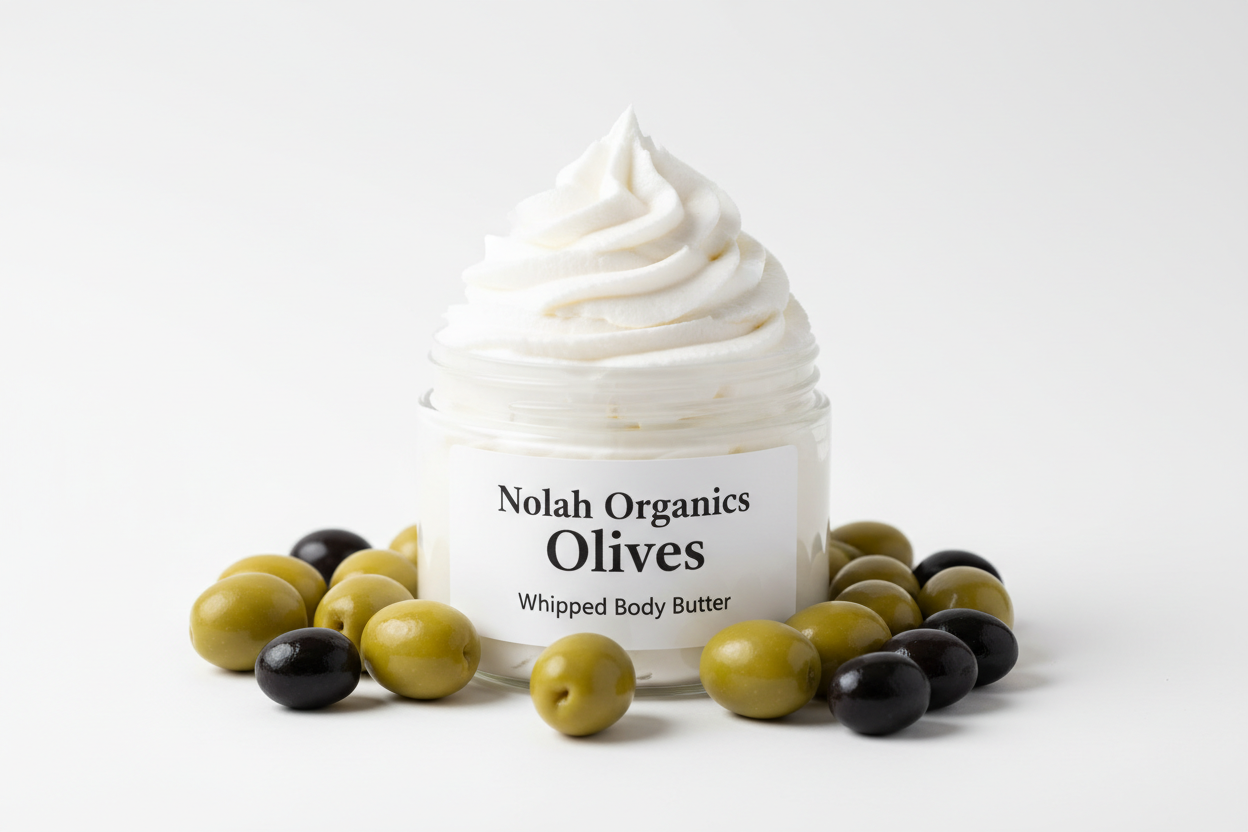Make me a photorealistic photo of my Nolah Organics Olives - Whipped Body Butter. The white body butter is in a clear jar and swirled high. The label is white with black writing. It is surrounded by shiny olives.